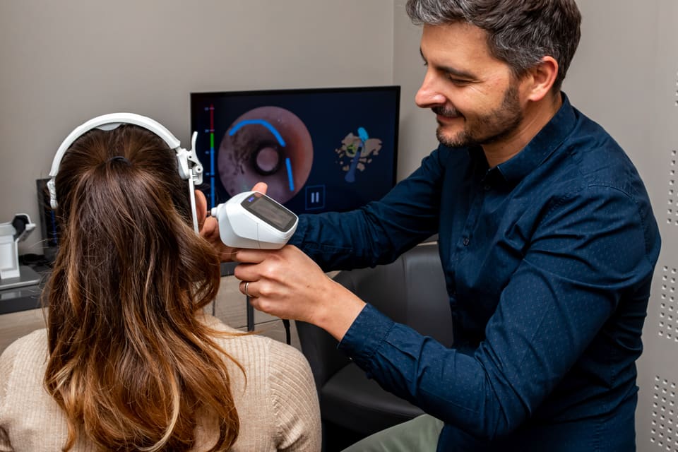 Un audioprothésiste procédant à un réglage sur une patiente.