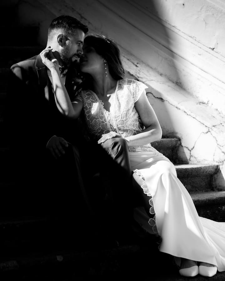 Les mariés assis dans un escalier, dans une lumière dure, en noir et blanc.